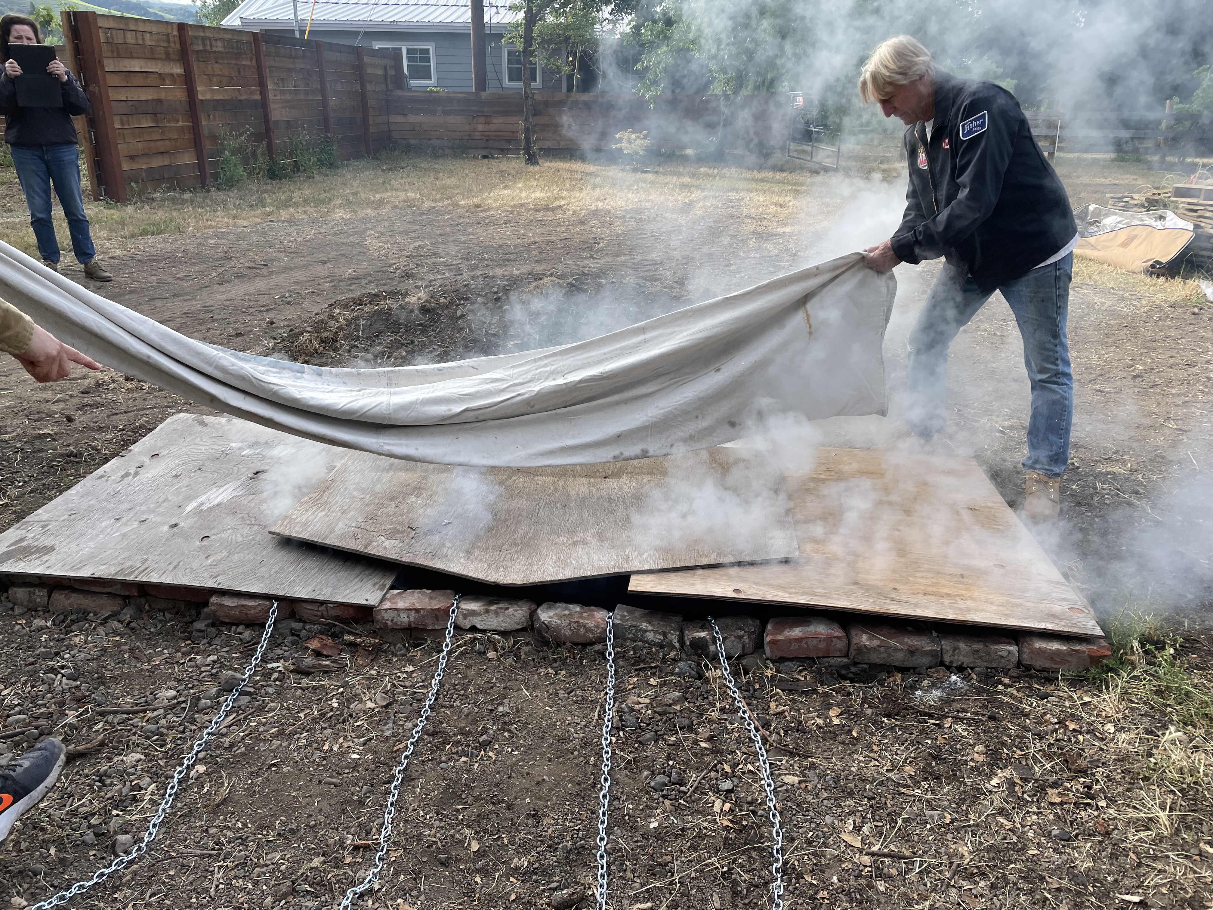 Laying canvas over the plywood lid. It's good to use a single piece of canvas or tarp big enough to cover the whole pit, as you can then easily fold it back and move all the soil off in a single action afterwards.